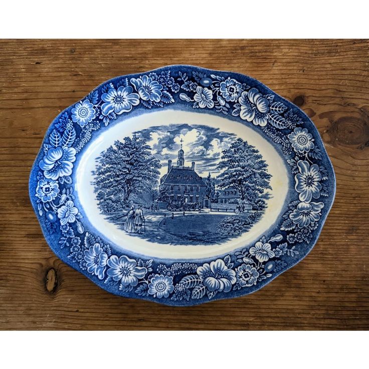 a blue and white plate with an image of a house in the woods on it