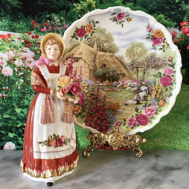 a decorative plate with a woman holding flowers on it and a garden scene behind it