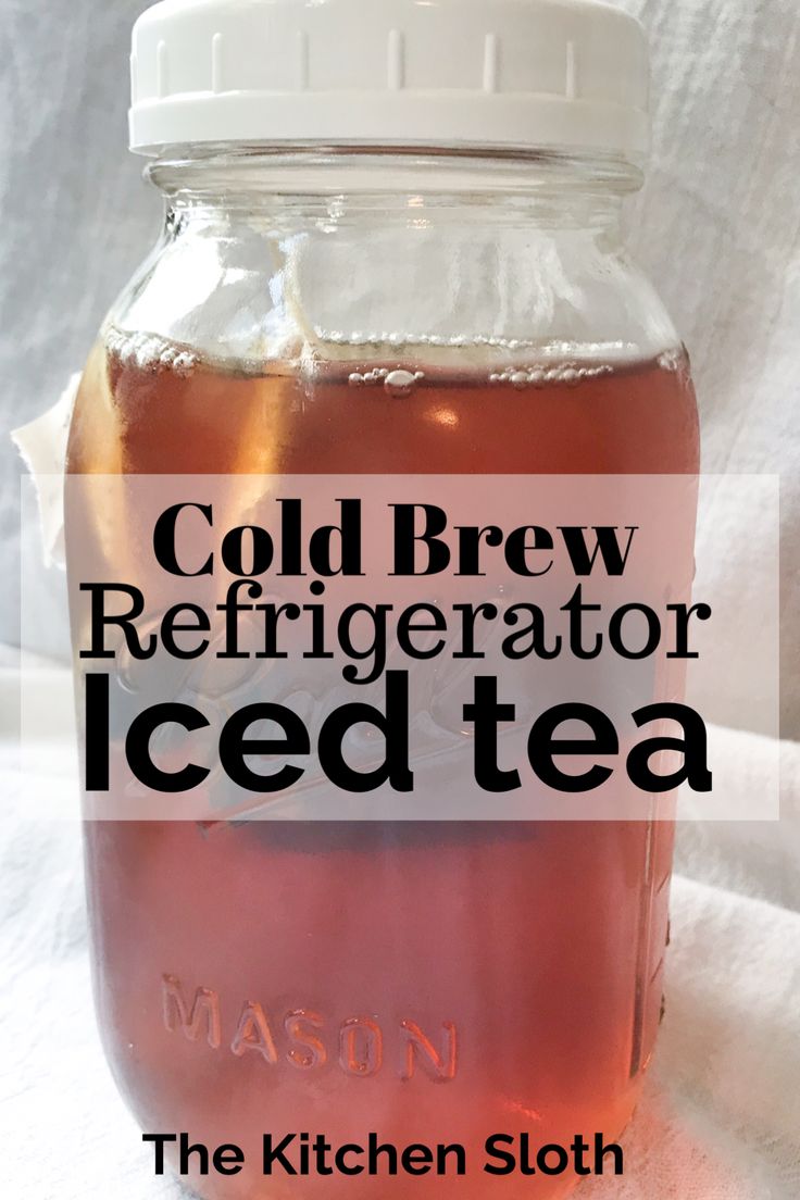 a mason jar filled with ice tea sitting on top of a white cloth covered table