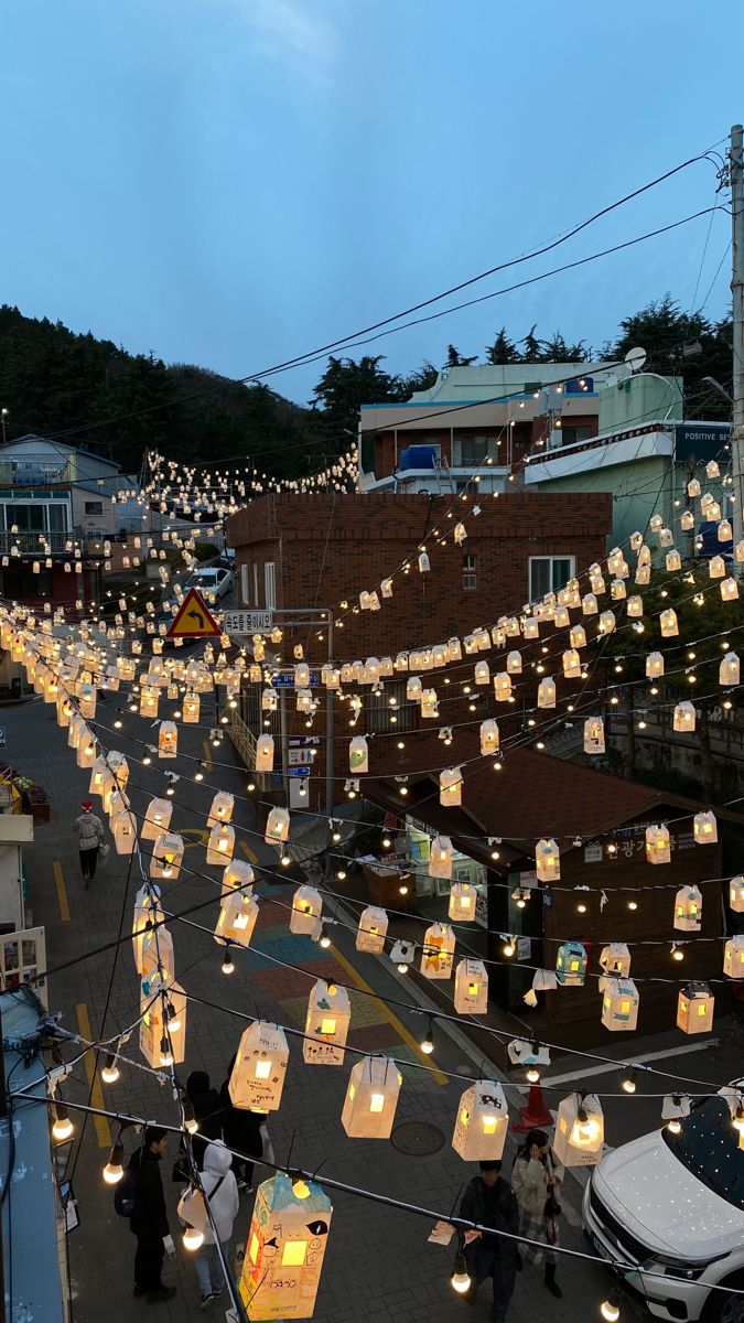 many paper lanterns are strung across the street with string lights hanging from it's sides