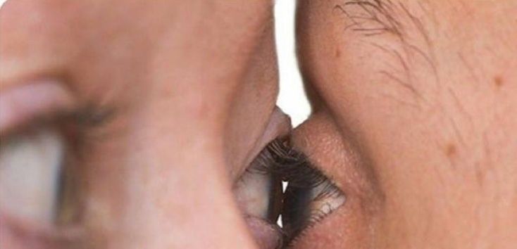 two people are looking into each other's eyes with one eye partially open and the other half closed