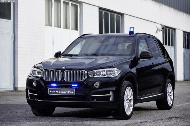 a black bmw x5 parked in front of a building with its lights turned on