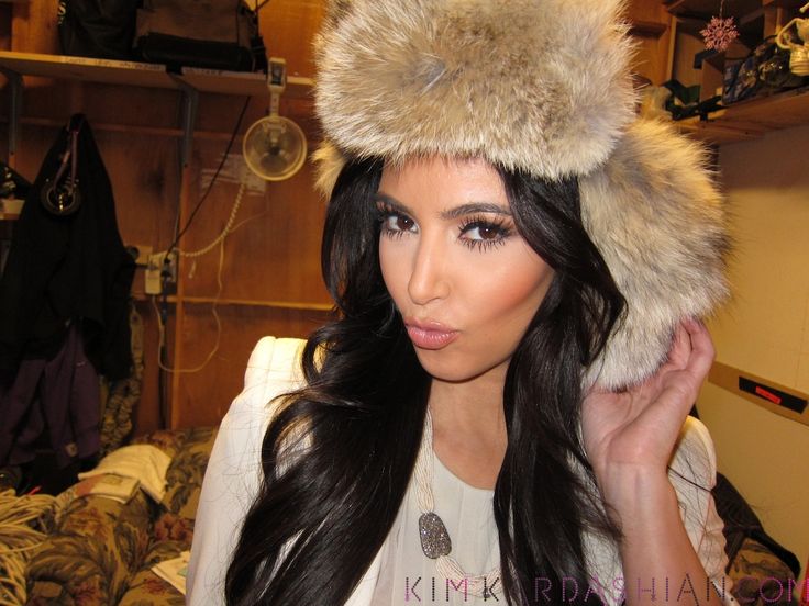 pictures of kim kardah wearing fur hats and black pants, while she is walking down the street