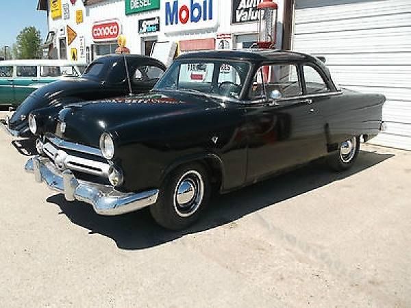 an old black car parked in front of a building