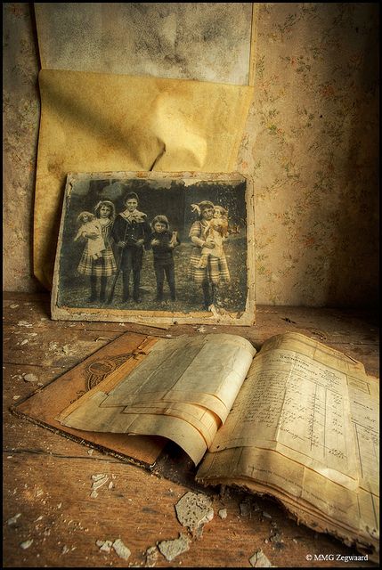 an old book sitting on top of a wooden table next to a torn piece of paper