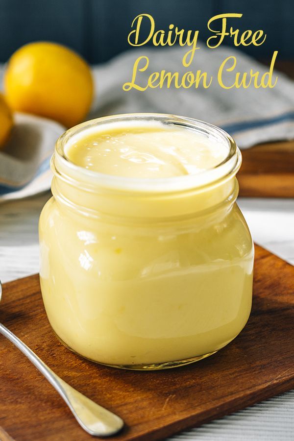 a glass jar filled with lemon curd sitting on top of a wooden cutting board