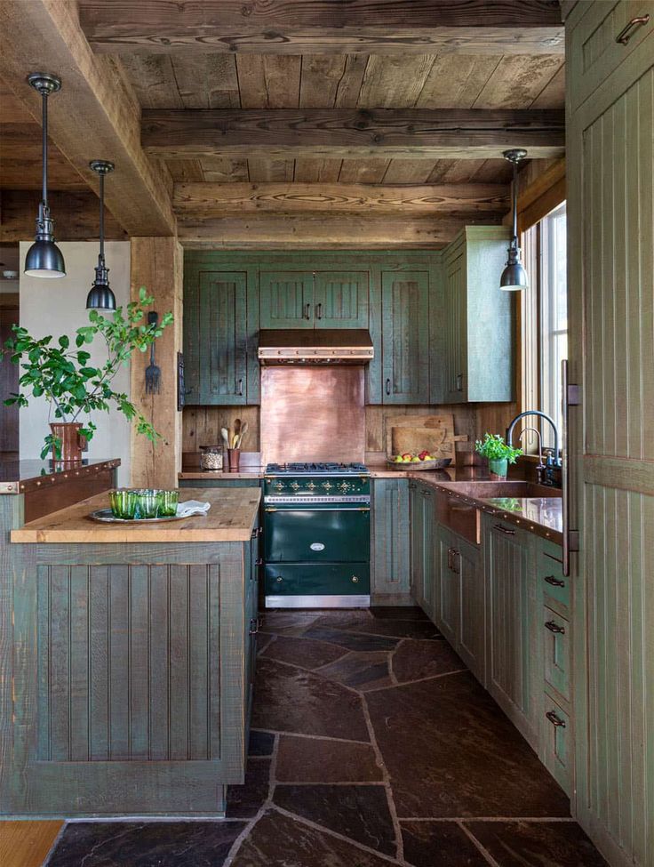 a kitchen with green cabinets and wood flooring, along with an island in the middle