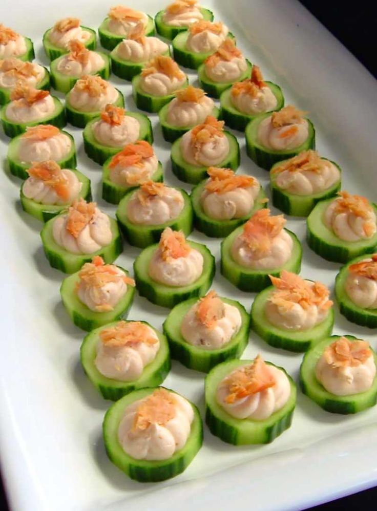 small cucumbers with shrimp on them sitting on a white platter, ready to be served