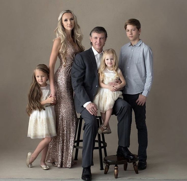 a family posing for a photo in front of a gray background with their two children