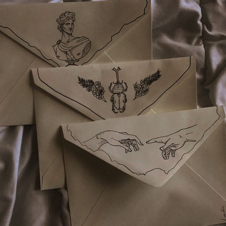 three envelopes with designs on them sitting on a bed