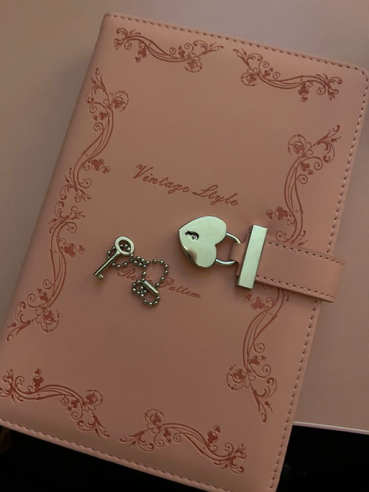 a pink book with keys and a keychain attached to it