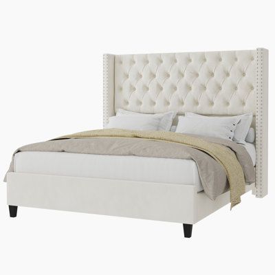 a white bed with tufted headboard and pillows on top of it, against a white background