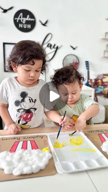 two young children are painting on paper plates with yellow and white paint in front of them