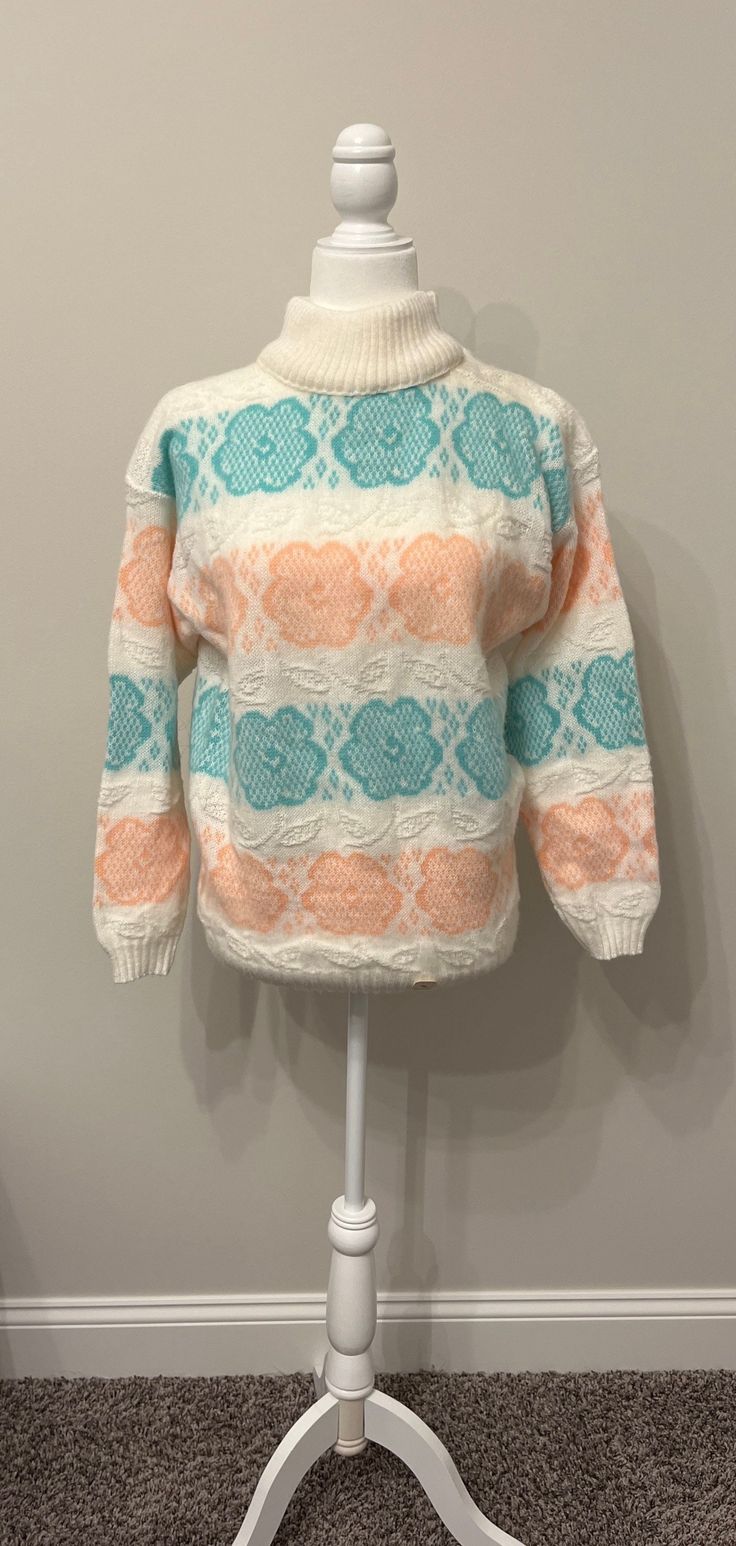 This sweater is adorable!  It's so 80s!  I loved acrylic sweaters like this back in the 80s.  They had a novelty cuteness to them.  Some had hearts, this one has flowers.  It has never been worn.  The base is a creamy white, with pastel aqua/seafoam green (leans a bit dark in the photos due to lighting) and pastel peach.  The peach looks a bit like orange sherbet.  Soft and oh so cozy, this one is great for those cool fall/winter nights!  It is a size Medium, with its original tag still stapled to the front.  Please see measurements below.  Super cute, with a slightly fuzzy texture.  I love it!  Thanks for looking! Measurements taken laying flat:  please double for chest & waist Armpit to armpit 19.75" Waist/middle 19" Sleeves from collar 24.5" Length 24" Cabin Sweater, 80s Inspired Outfits, Outfits Pastel, 80s Pastel, Novelty Sweater, Fuzzy Texture, 80s Floral, Orange Sherbet, 80s Sweater