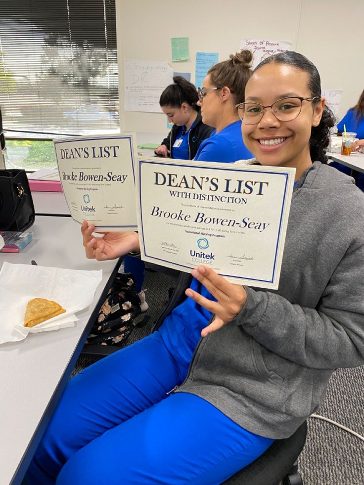 a woman sitting in front of a desk holding up a sign that reads dear's list