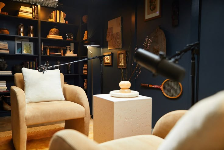 a living room with two chairs and a lamp in the corner next to bookshelves