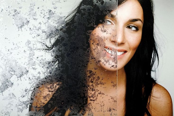 a woman with long black hair is smiling and posing for the camera in front of an artistic background