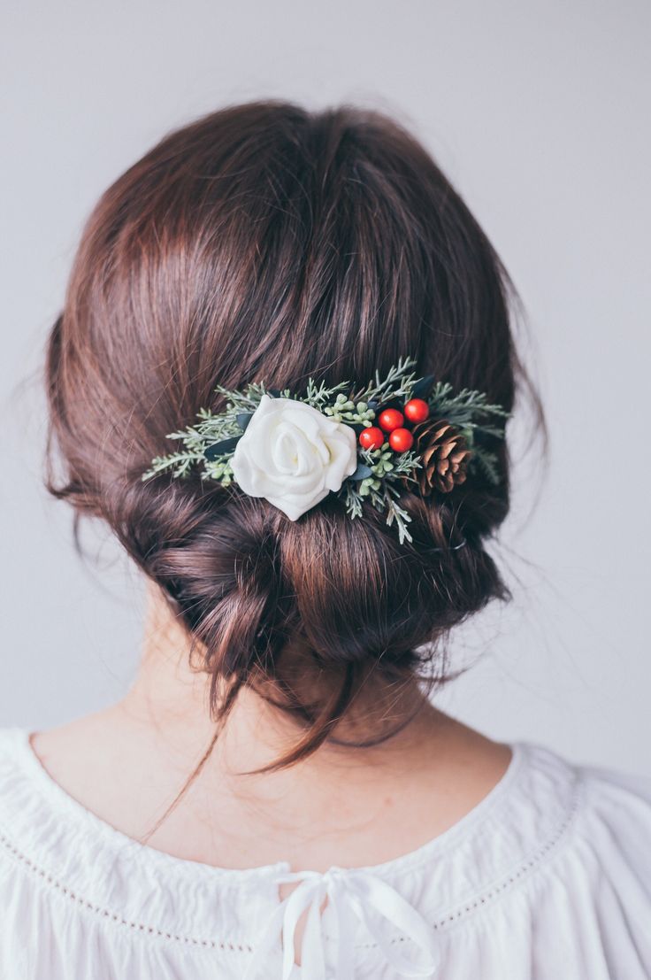 a woman wearing a white flower and greenery in her hair with red berries on it