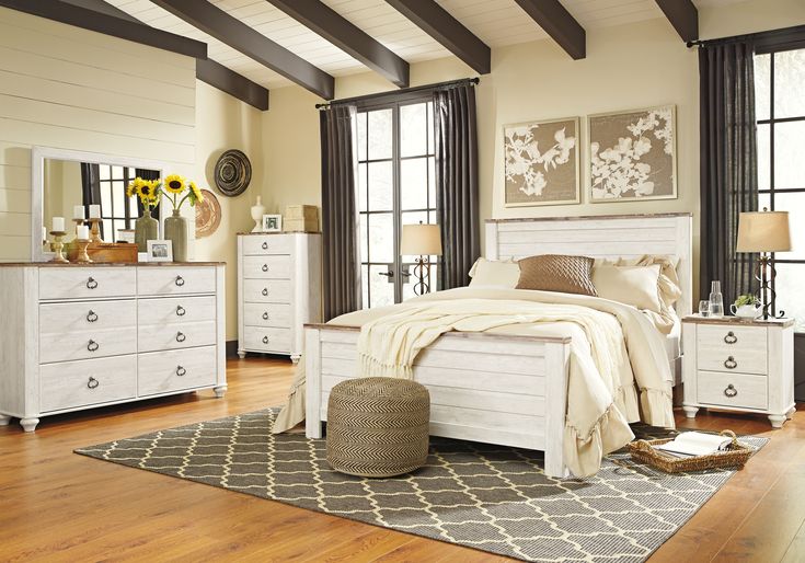 a white bed sitting on top of a wooden floor next to a dresser and mirror