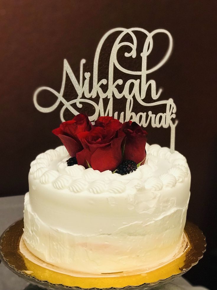 a white cake with red roses on top and the name nukah makraki