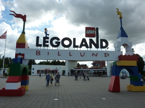 the entrance to legoland is brightly colored and has people walking underneath it on a cloudy day