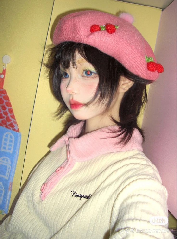 a woman wearing a pink hat with strawberries on her face and black hair in front of a yellow wall