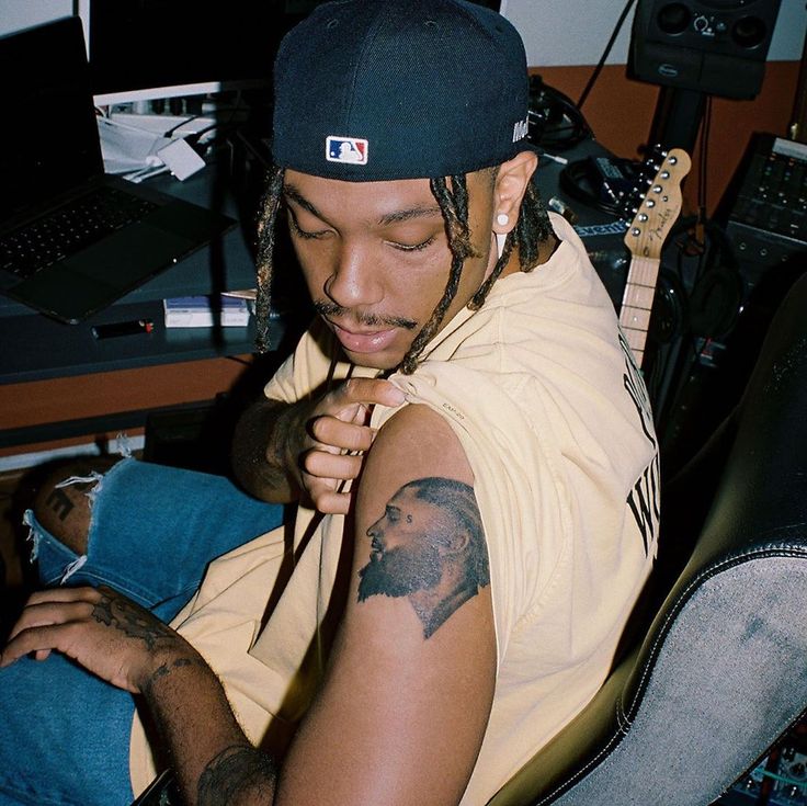 a man with dreadlocks sitting in front of a guitar