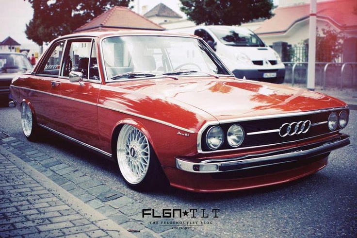 an old red car is parked on the street