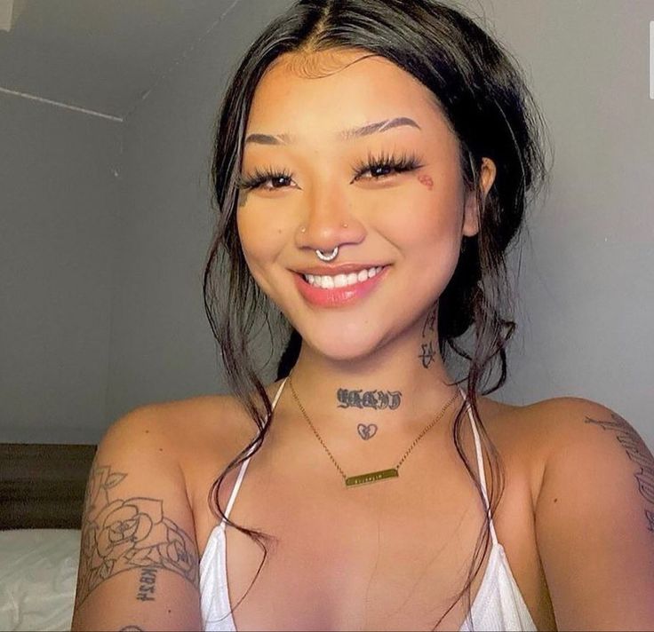 a woman with tattoos on her chest smiling at the camera