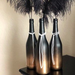 three black vases with pearls and feathers in them