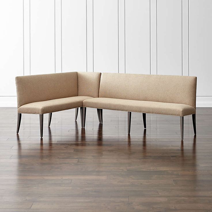 a beige couch sitting on top of a hard wood floor next to a white wall