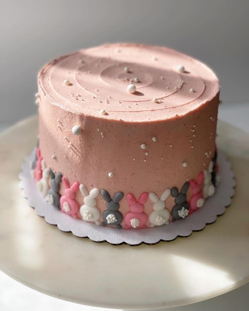 a pink frosted cake sitting on top of a white plate with polka dot decorations