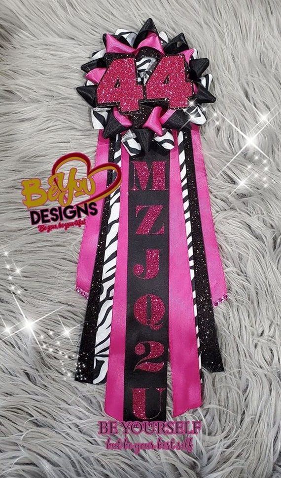 a pink and black ribbon with zebra print on the side, sitting on a furry surface