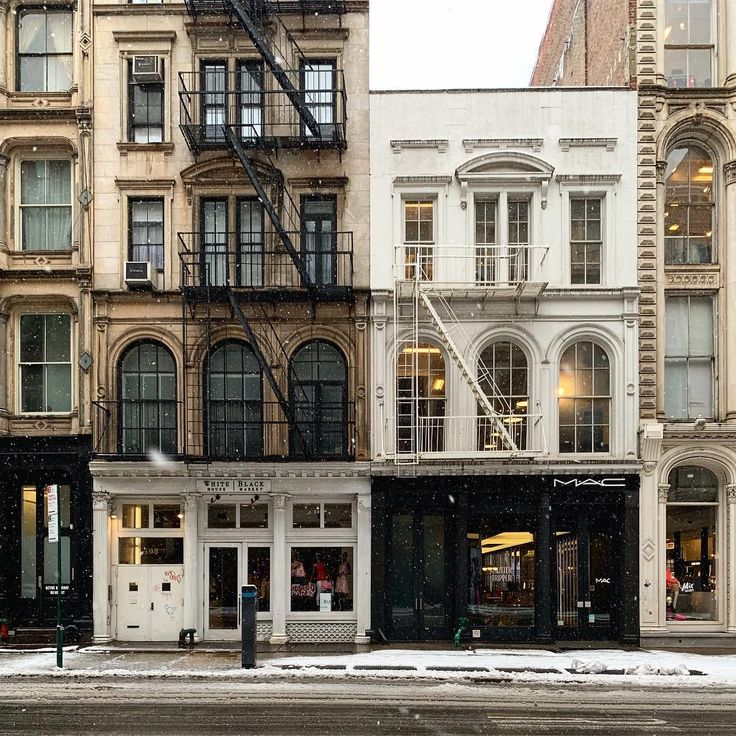 an empty street in front of several buildings with snow on the ground and fire escapes