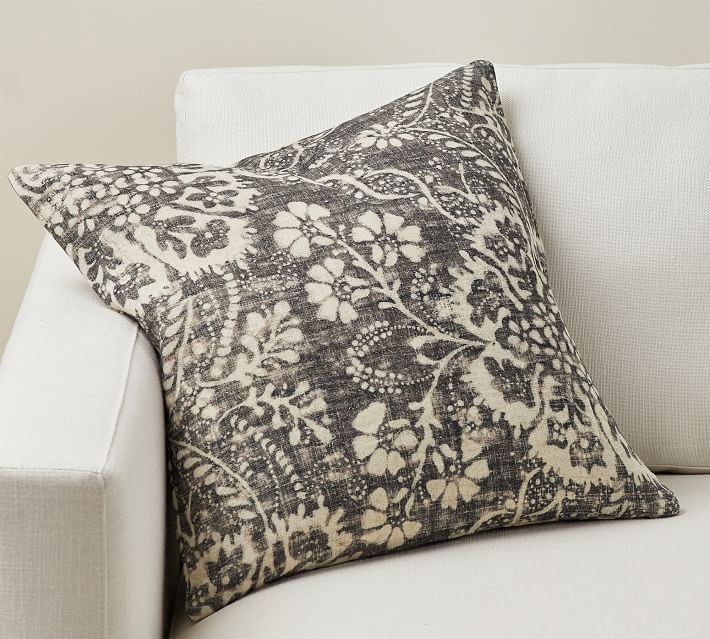 a white couch with a black and white floral pillow on it's backrest