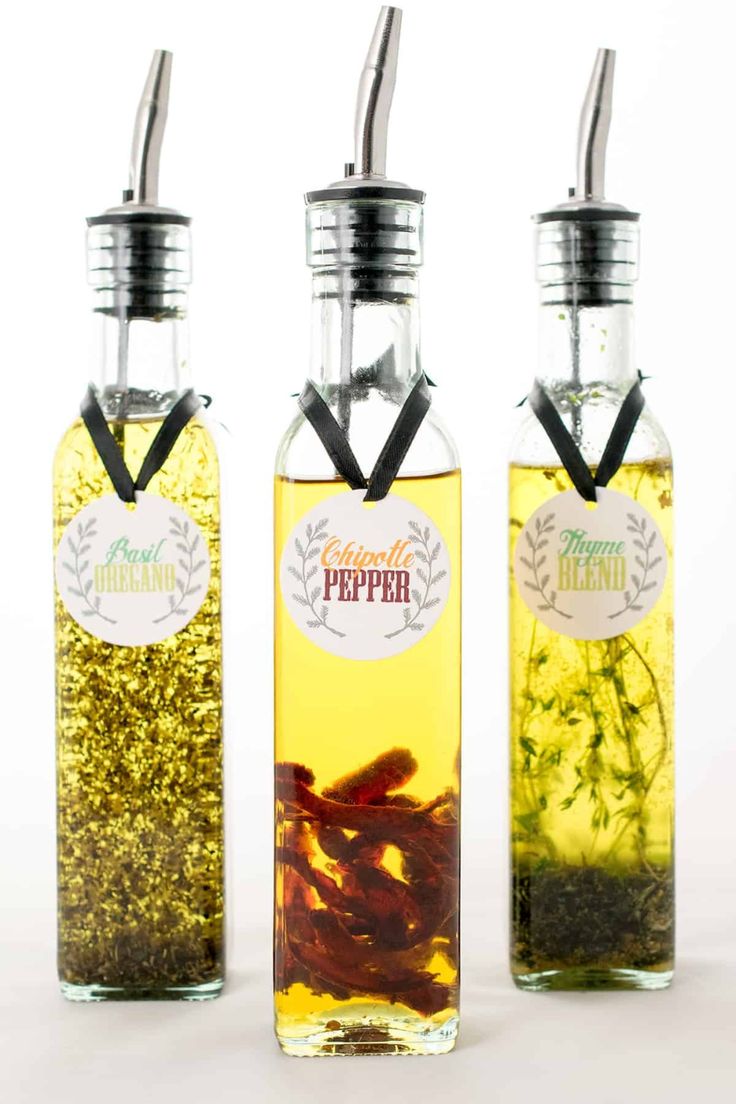 three bottles filled with different types of liquid and some sort of food in them on a white surface