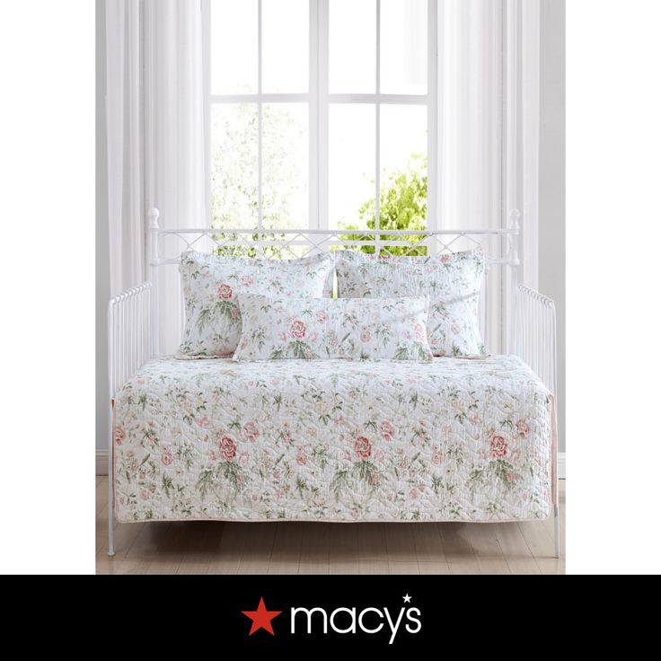 a white daybed with pink flowers on it in front of a window