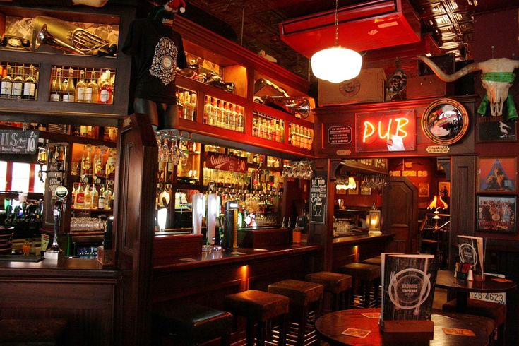 a dimly lit bar with lots of liquor bottles on the shelves and lights hanging from the ceiling