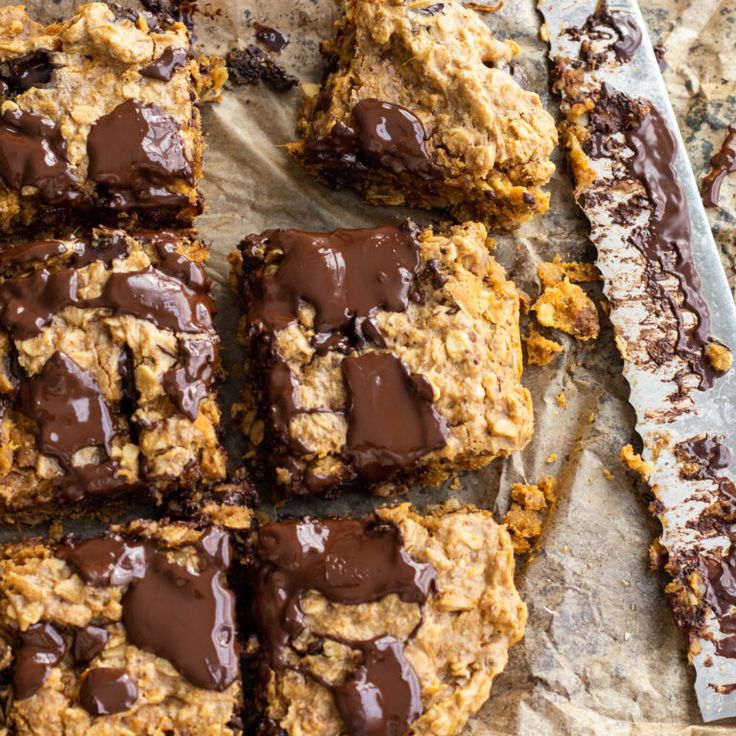 chocolate - covered cookies and oatmeal bars are arranged on top of parchment paper