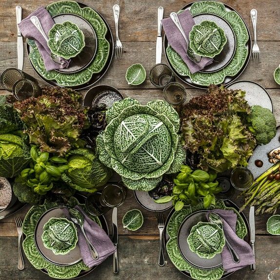 an overhead view of a table set with green plates and silverware, including broccoli