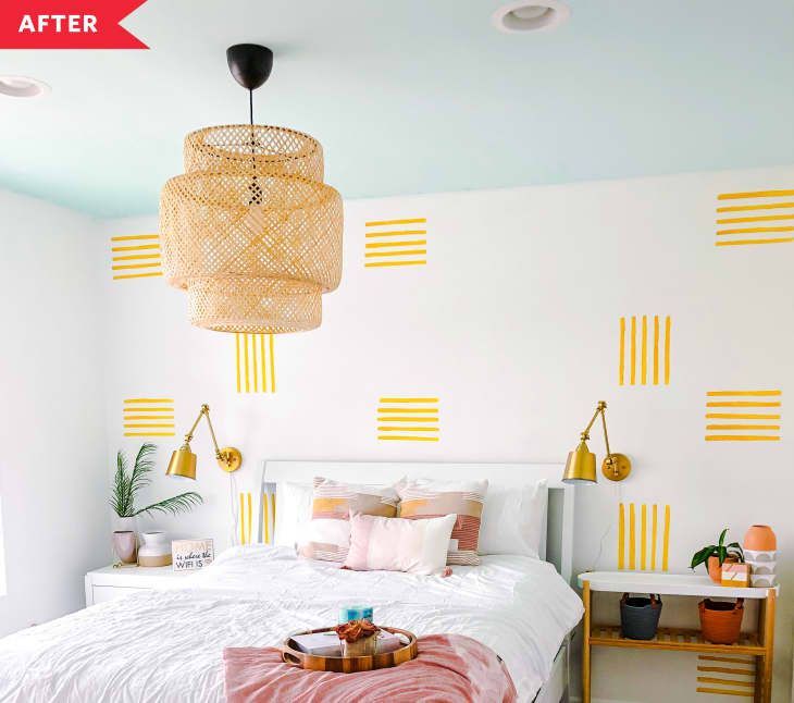 a bedroom with yellow stripes painted on the walls and a white bed topped with pink pillows