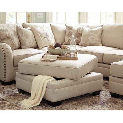 a living room filled with lots of furniture and pillows on top of a rug in front of a window