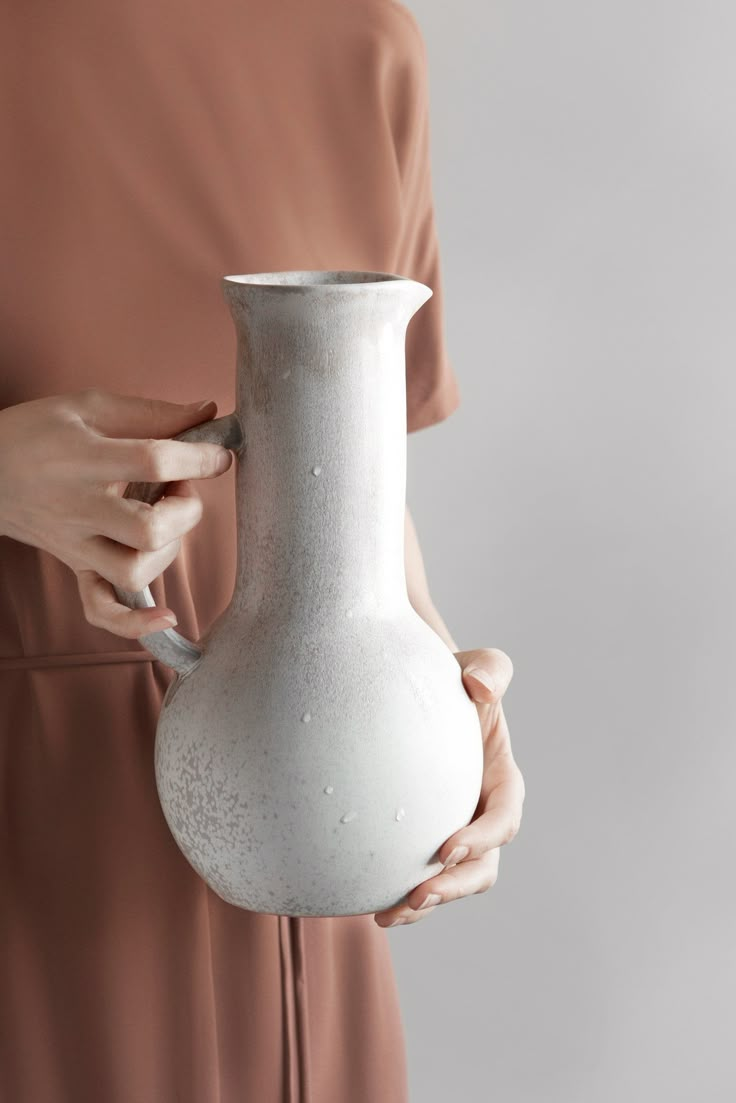 a woman holding a white vase in her hands