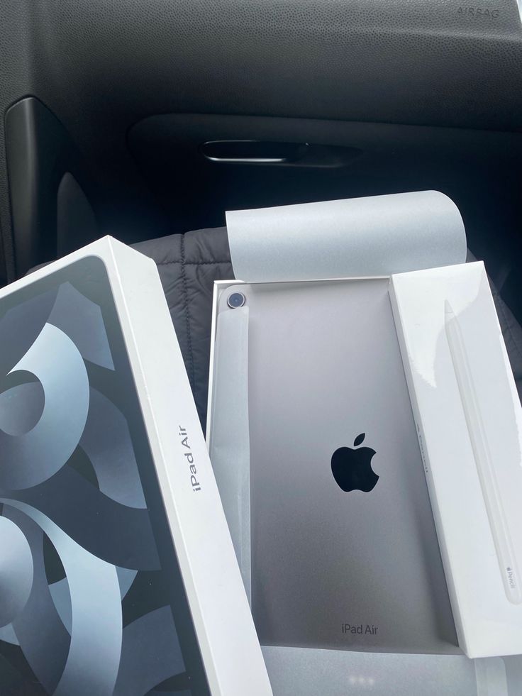 an apple computer sitting in the back seat of a car with its box open next to it