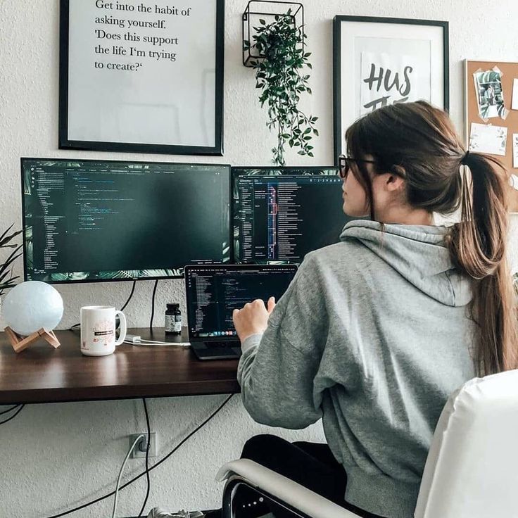 a woman sitting at a desk in front of two computer monitors