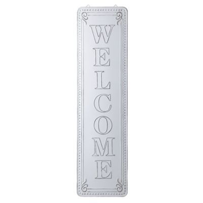 a white welcome sign hanging from the side of a wall with an ornate design on it