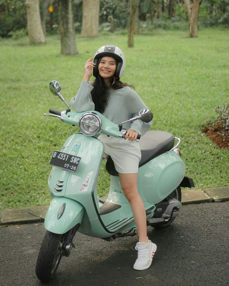 a woman sitting on top of a blue scooter