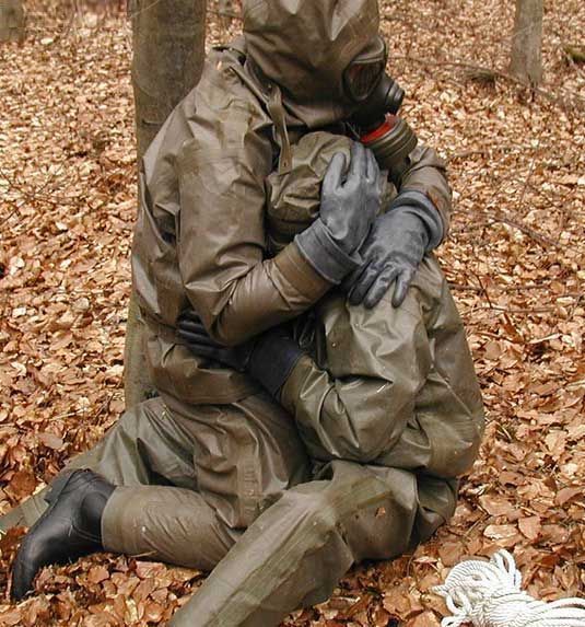 a man in a gas mask sitting on the ground next to a tree