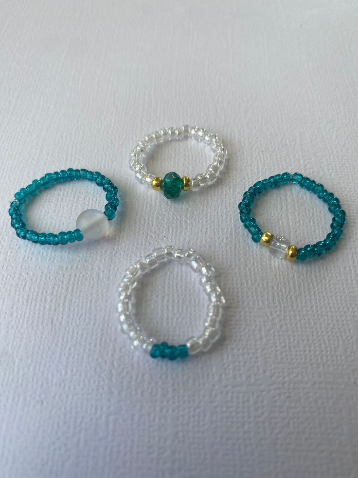 three bracelets with pearls and beads on a white surface, one is blue the other is white