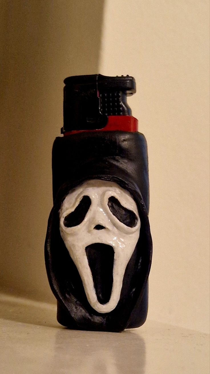 a black lighter with a white mask on it's face and tongue sticking out